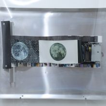 Arya Tabandehpoor, “Day, Night, Noise”, from “Retooling” series, (part of a photo-cutting machine, photographs printed on a metallic paper, offset plate, wooden frame, translucent plexiglas, adaptor, on-off switch, double-sided tape, screw, washer, green ink, 90 degrees brace), 70 x 75 cm, 2019 