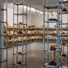 Mahsa Aleph, “Corpse” , from “The Container made of the Contained” series, ” series, installation made of thirty-five thousand date kernels in 4 metal columns consists of 10 shelves, processed by turmeric, mold, oil, and soot, installation view, 2019